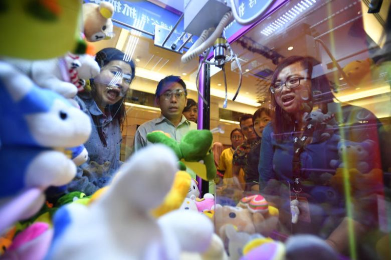 Ms Nur Khadijah Mohd Ripin (extreme right) trying her luck at the claw machine at the SPH Charity Carnival.